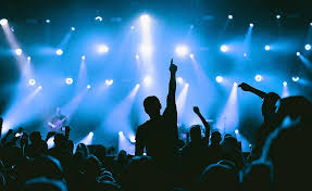 Crowd enjoying a live concert in Lima, Peru, at night with colorful stage lights.