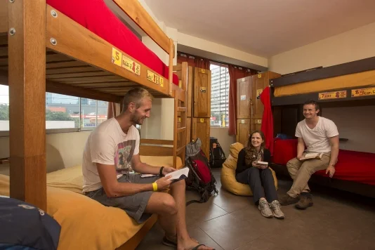 Backpackers socializing in a vibrant hostel common area.